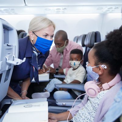 A flight attendant helps a young girl in flight