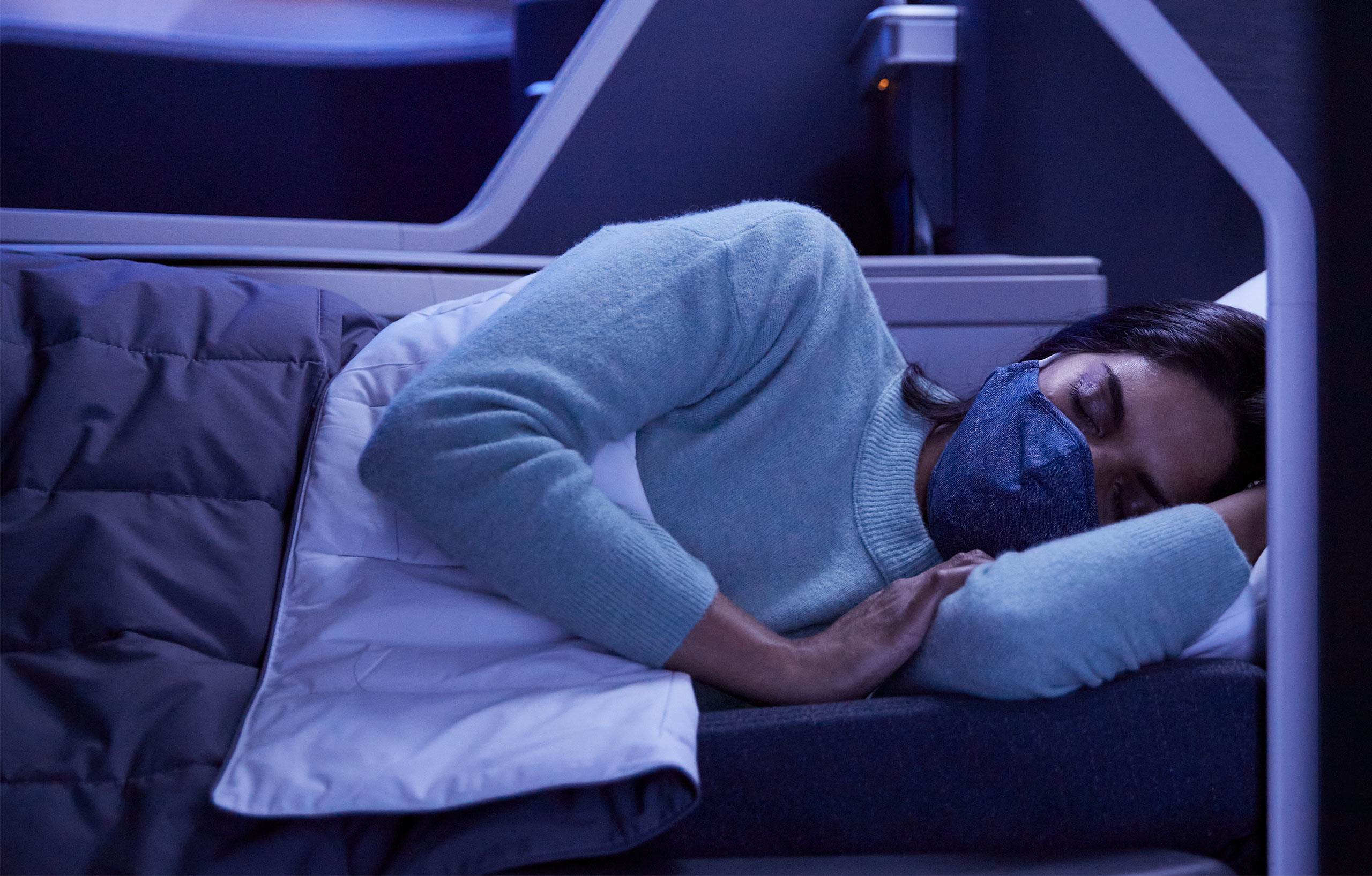 A passenger sleeps in a lay flat seat on board a flight
