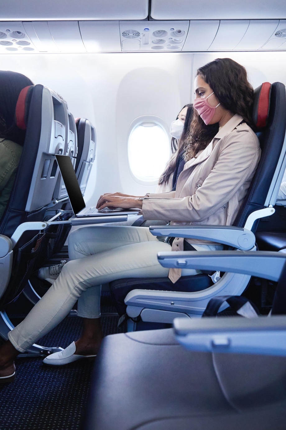 A woman works on her laptop in a Main Cabin Extra seat